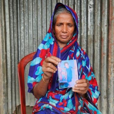 An older woman holds up a photo of a child