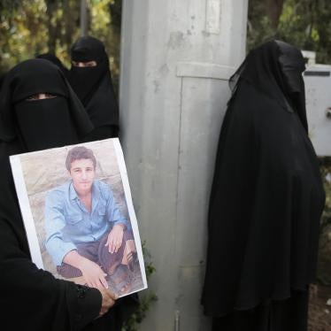 A woman holds her son's picture as she waits for Houthi prisoners to arrive at Sanaa airport, Yemen.