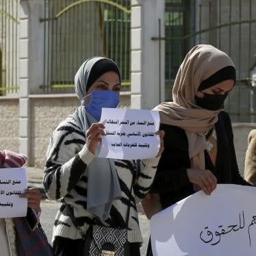 Women hold signs in Arabic during a protest 