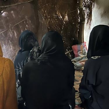 A group of women seated on the floor with their faces obscured 