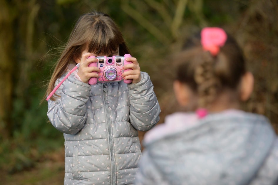 Two young girls are playing with their cameras in a garden, Osterode, Germany, January 8, 2016. 