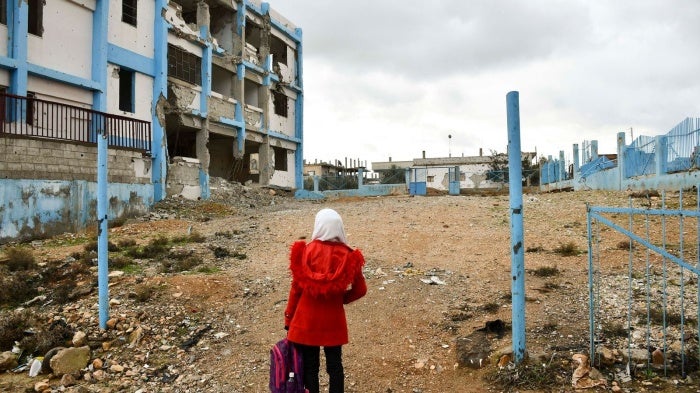 A 14-year-old girl looks at her old school, which was damaged by conflict, in Dara’a Albalad, Syria, on February 7, 2022. © UNICEF/UN0635253/Shahan